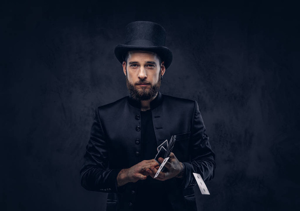 Magician showing trick with playing cards on a dark background. - Foto, Bild