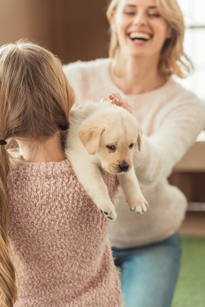 happy mother and daughter playing with adorable labrador puppy - Фото, зображення