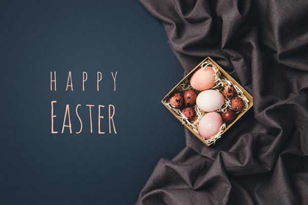 Pääsiäiskonsepti, värikäs pääsiäismuna harjalla ja koristeet mustalla taustalla tekstillä, ylhäältä
 - Valokuva, kuva