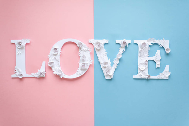 Photo inscription love made of leaves and flowers on blue and pink background - Фото, изображение