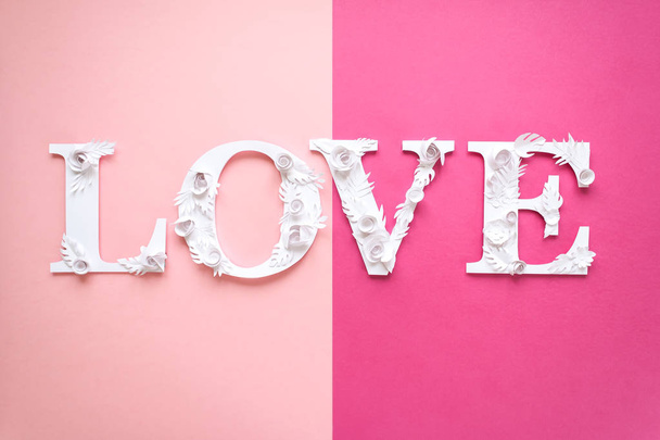 Photo inscription love made of leaves and flowers on pink background - Fotografie, Obrázek