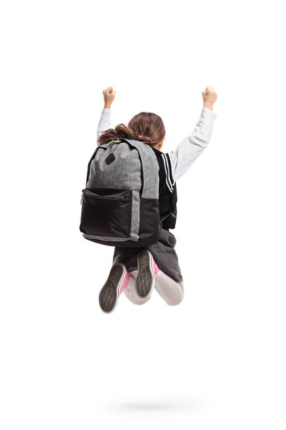 Rear shot of a schoolgirl with a backpack jumping and gesturing happiness isolated on white background - Foto, Imagen