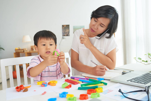 Werken bij huis, kind spelen met kleurrijke speelgoed zakenvrouw - Foto, afbeelding