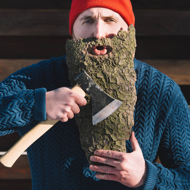 portrait of man with beard made of wood bark and axe in hand outdoors - Zdjęcie, obraz