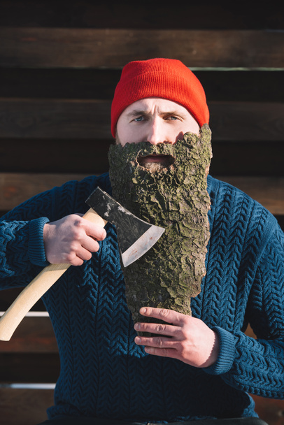 portrait of man with beard made of wood bark and axe in hand outdoors - Foto, Imagen