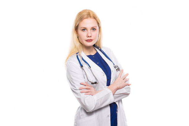 Молодая уверенная в себе женщина-врач со стетоскопом стоит со скрещенными руками и смотрит в камеру
 - Фото, изображение