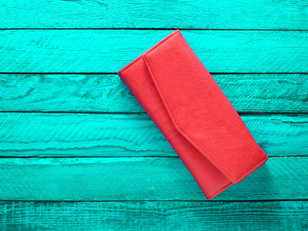 Modische rote Handtasche auf türkisfarbenem Holzhintergrund. Ansicht von oben. Trend zum Minimalismus. - Foto, Bild
