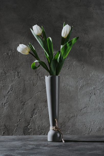 コンクリートの表面に灰色の花瓶の白い春チューリップ - 写真・画像