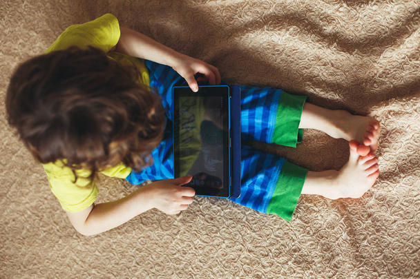 Little boy using tablet on a bed. Top view - Photo, image