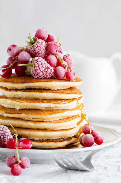 Stack of pancakes with raspberry, red currant, cream and honey on white table cloth - Foto, Imagem