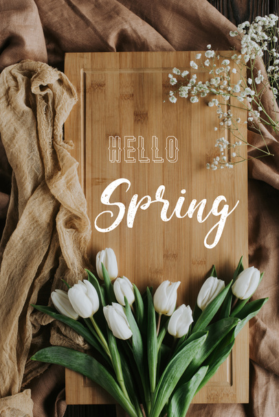 top view of white tulips on wooden board with hello spring lettering - Foto, Imagem