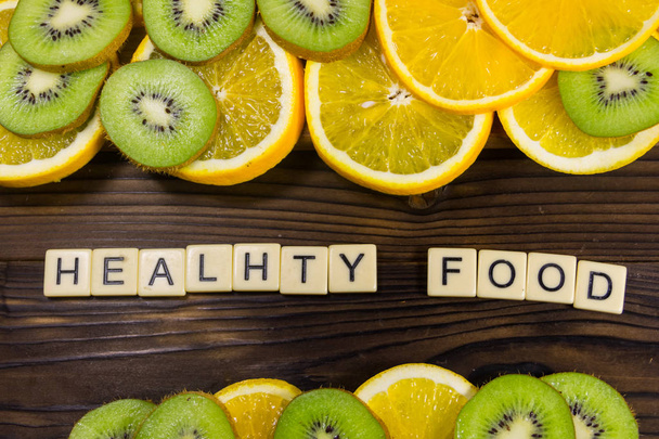 Frutas de kiwi fatiadas e laranjas com inscrição "comida saudável"
 - Foto, Imagem