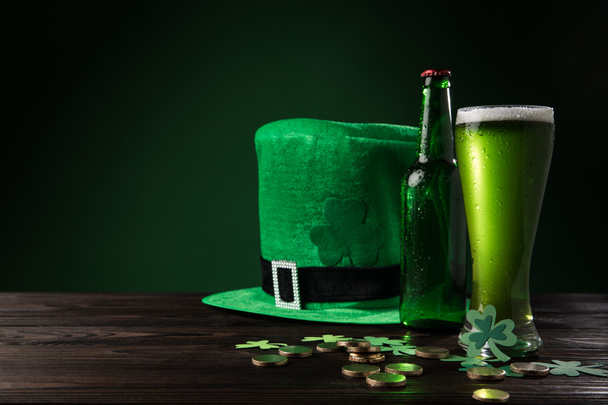 grüner Hut mit grünem Bier und Münzen auf Holztisch, st patricks day concept - Foto, Bild