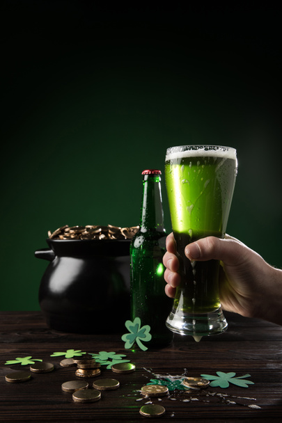 oříznutý obraz člověka drží sklo zelené pivo s hrnec mincí na stole, st patricks day koncept - Fotografie, Obrázek