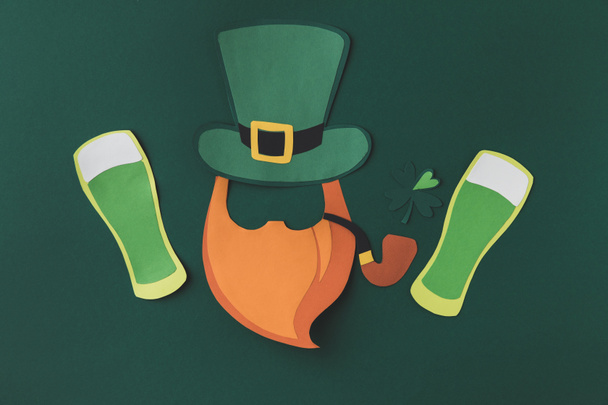 top view of paper decoration of leprechaun and beer for st patricks day isolated on green - Zdjęcie, obraz