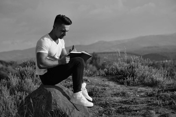 Pensive muscular man with book outdoor - Photo, Image