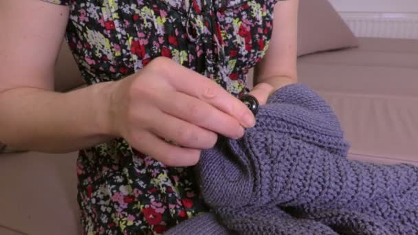 Γυναίκα ράβει κουμπί στη ζακέτα - Πλάνα, βίντεο