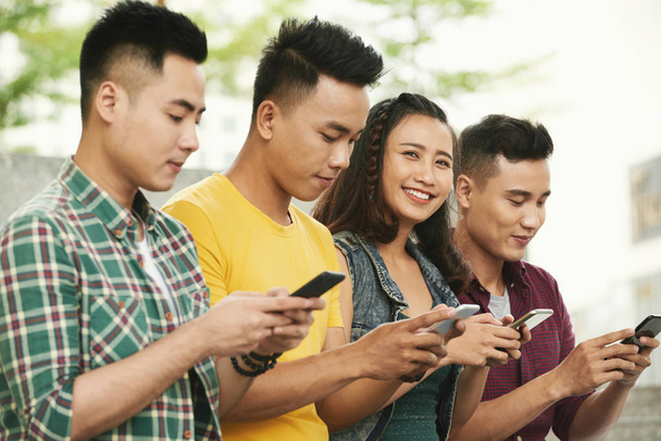 Wesoły młodych ludzi za pomocą mobilnej aplikacji na smartfony - Zdjęcie, obraz