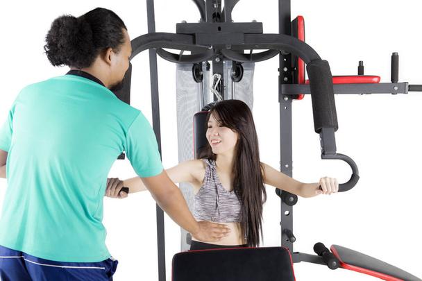 Trainer and girl with weight machine on studio - Фото, изображение