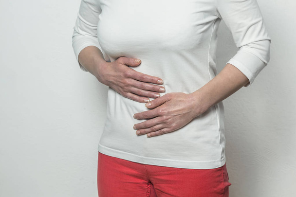 Una mujer sostiene sus manos sobre su vientre. períodos
 - Foto, imagen