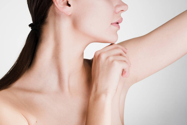 a woman looks after the armpits on a gray background - Foto, Imagen