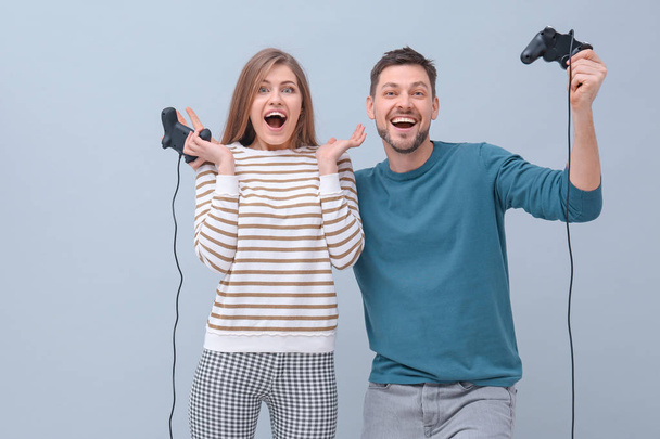 Emotional couple with video game controllers on color background - Фото, зображення