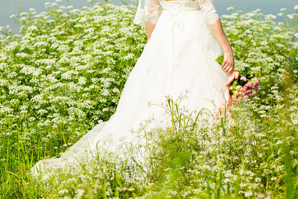 Невеста в белом платье в парке со свадебным букетом в руках
 - Фото, изображение