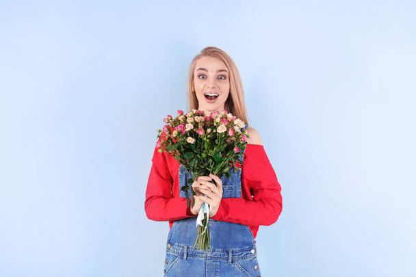 Beautiful young woman with bouquet of roses on color background - Фото, изображение