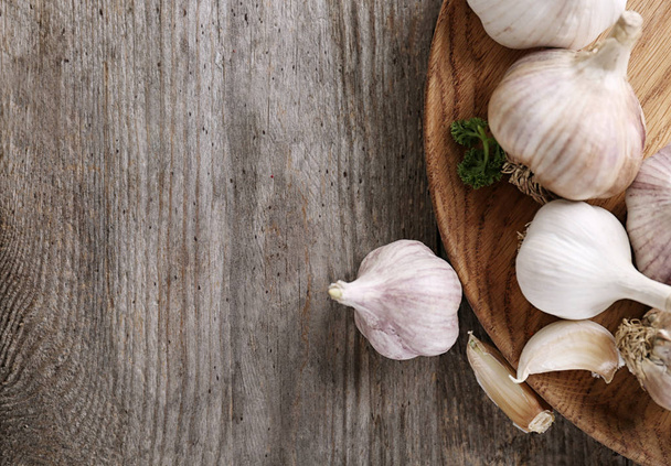 Plate with fresh garlic on wooden table - Photo, image