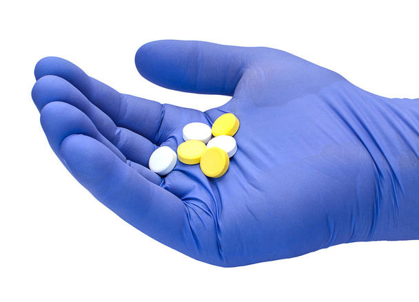 Hand in medical rubber glove with pills  - Foto, afbeelding