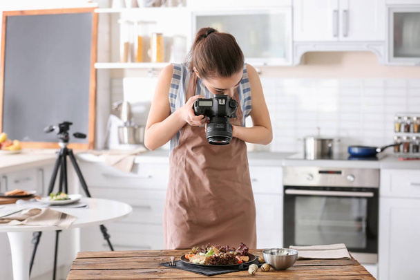 キッチンで静物写真を撮るプロのカメラを持つ若い女性 - 写真・画像