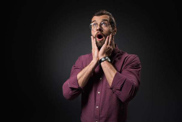 portrait of shocked man in eyeglasses looking away isolated on black - Foto, immagini