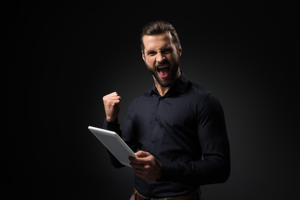 retrato de hombre excitado con tableta digital aislada en negro
 - Foto, Imagen