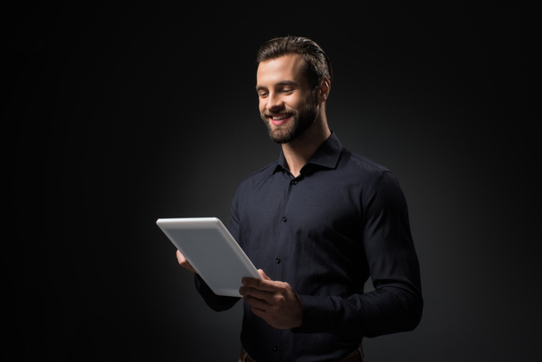 Porträt eines lächelnden Mannes mit digitalem Tablet isoliert auf schwarz - Foto, Bild