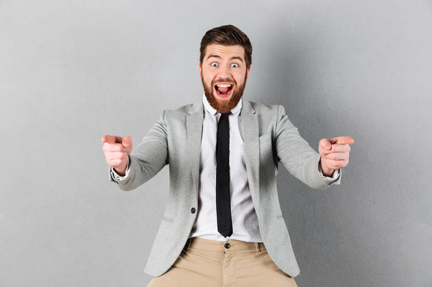 Portrait of an excited businessman dressed in suit standing - Φωτογραφία, εικόνα