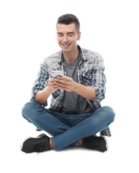 Attractive young man with mobile phone on white background - Fotoğraf, Görsel