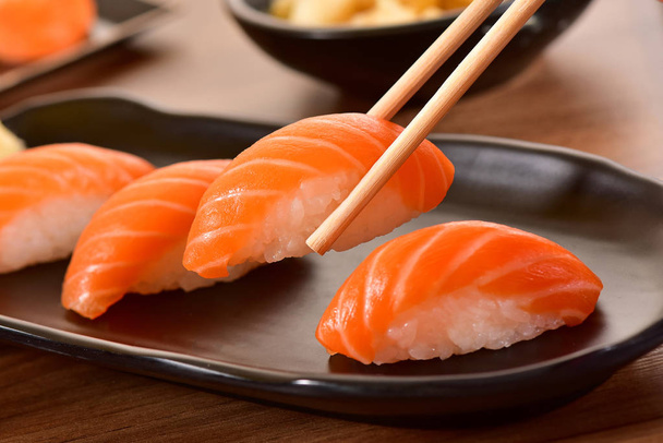Chopstiks sosteniendo un sushi nigiri
 - Foto, Imagen