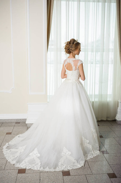 bella sposa in un abito da sposa in una lussuosa stanza bianca con un grande lampadario
 - Foto, immagini
