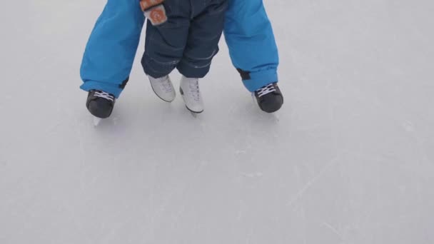 Перші кроки маленької дитини на ковзанах. Тато вчить дитину, щоб кататися на ковзанах і володіє своїми ручками. Сім'ї та активного відпочинку - Кадри, відео