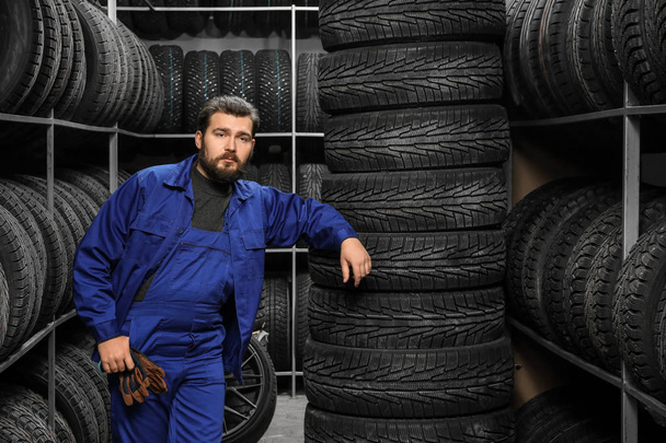 Male mechanic near tires in automobile store - Φωτογραφία, εικόνα