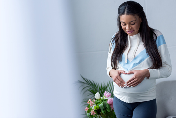african american Kobieta w ciąży, co serce symbol z ręce na brzuchu - Zdjęcie, obraz