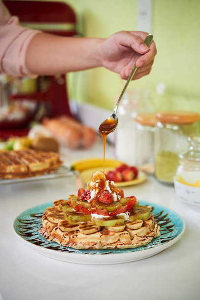Pasticcere versando sciroppo di caramello su waffle con frutta fresca
 - Foto, immagini