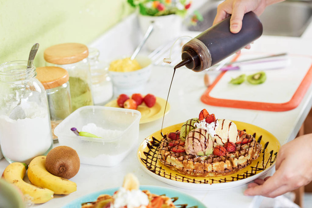 Pasticciere con sciroppo di cioccolato per decorare il piatto con waffle
 - Foto, immagini