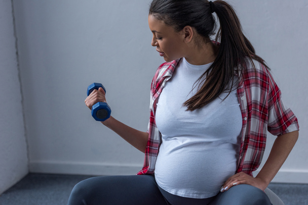 アフリカ系アメリカ人の妊婦のダンベルのトレーニング - 写真・画像