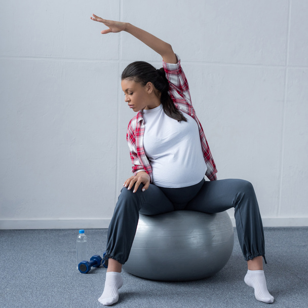 african american pregnant woman stretching on fit ball - Фото, зображення