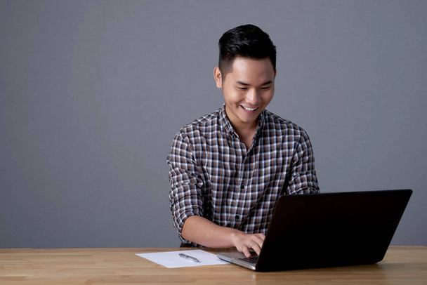 mladý podnikatel sedí v kanceláři a na slibný projekt s pomocí přenosného počítače - Fotografie, Obrázek