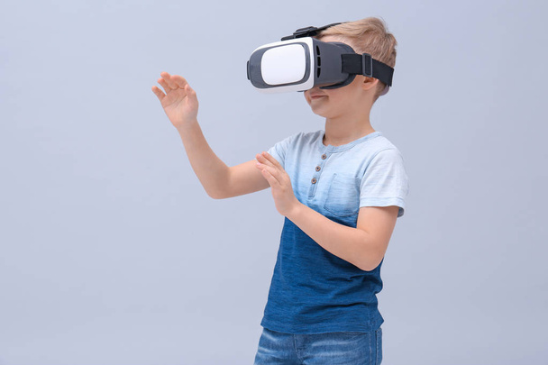 Cute boy with virtual reality headset on color background - Фото, зображення