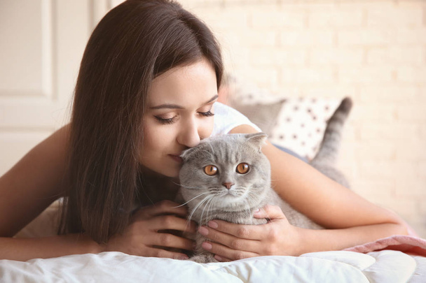 自宅のベッドの上のかわいいペットの猫を持つ若い女性 - 写真・画像