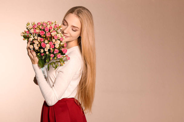 Beautiful young woman with bouquet of roses on color background - Fotoğraf, Görsel
