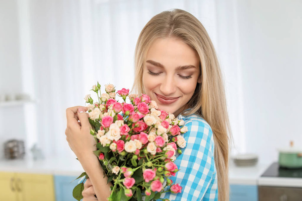 Beautiful young woman with bouquet of roses at home - Fotó, kép